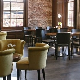 Zaal bij Restaurant Bij5 met groene ronde zitjes en donkere tafels met houten stoelen