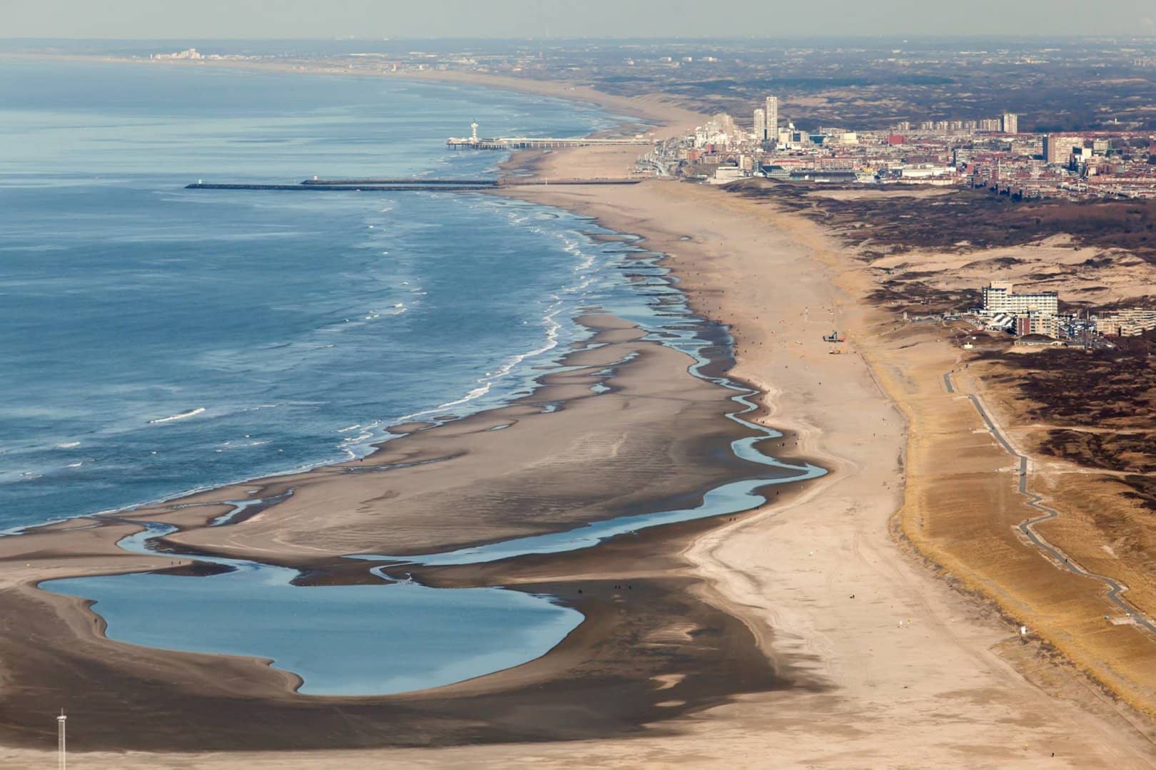 luchtfoto van de Zandmotor bij de kust van Monster met een leeg strand een binnenmeer