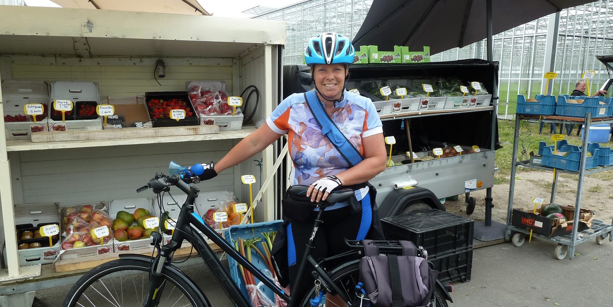 Marja van der Ende poseert met haar fiets voor een stalletje met streekproducten uit het Westland