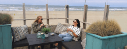 twee vriendinnen genieten in een loungebank bij een strandtent van een vriendinnendag weg in het Westland