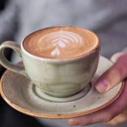 hand met kopje koffie in een groen kopje bij NON Bar in het Westland