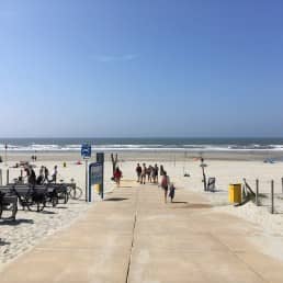 strandopgang Vlugtenburg naar het strand in het westland op een zonnige zomerse dag met mensen die met strandspullen richting het strand lopen