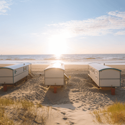 5 pipowagens op het strand van het Westland met duinen op de voorgrond en de zee in de achtergrond