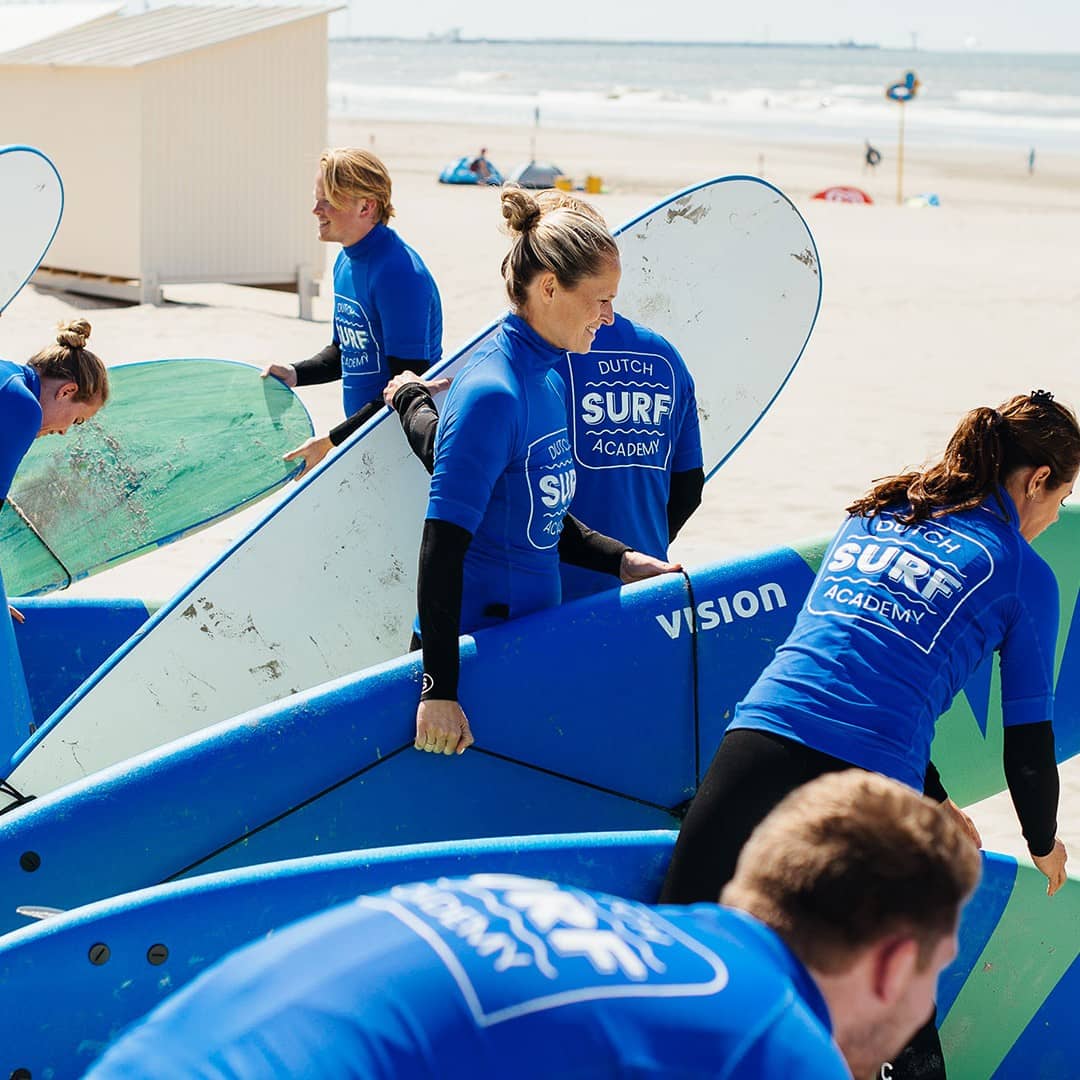groep cursisten op het strand tijdens een les golfsurfen van Dutch Surf Academy in het Westland