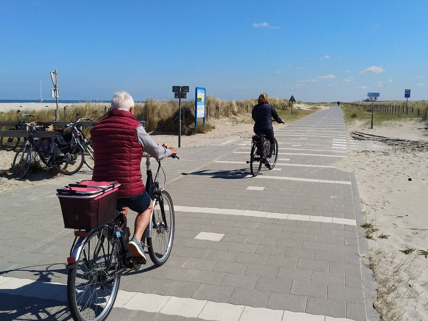 Oudere man en vrouw op de fiets op het fietspad door de duinen bij strandopgang Molenslag in het Westland