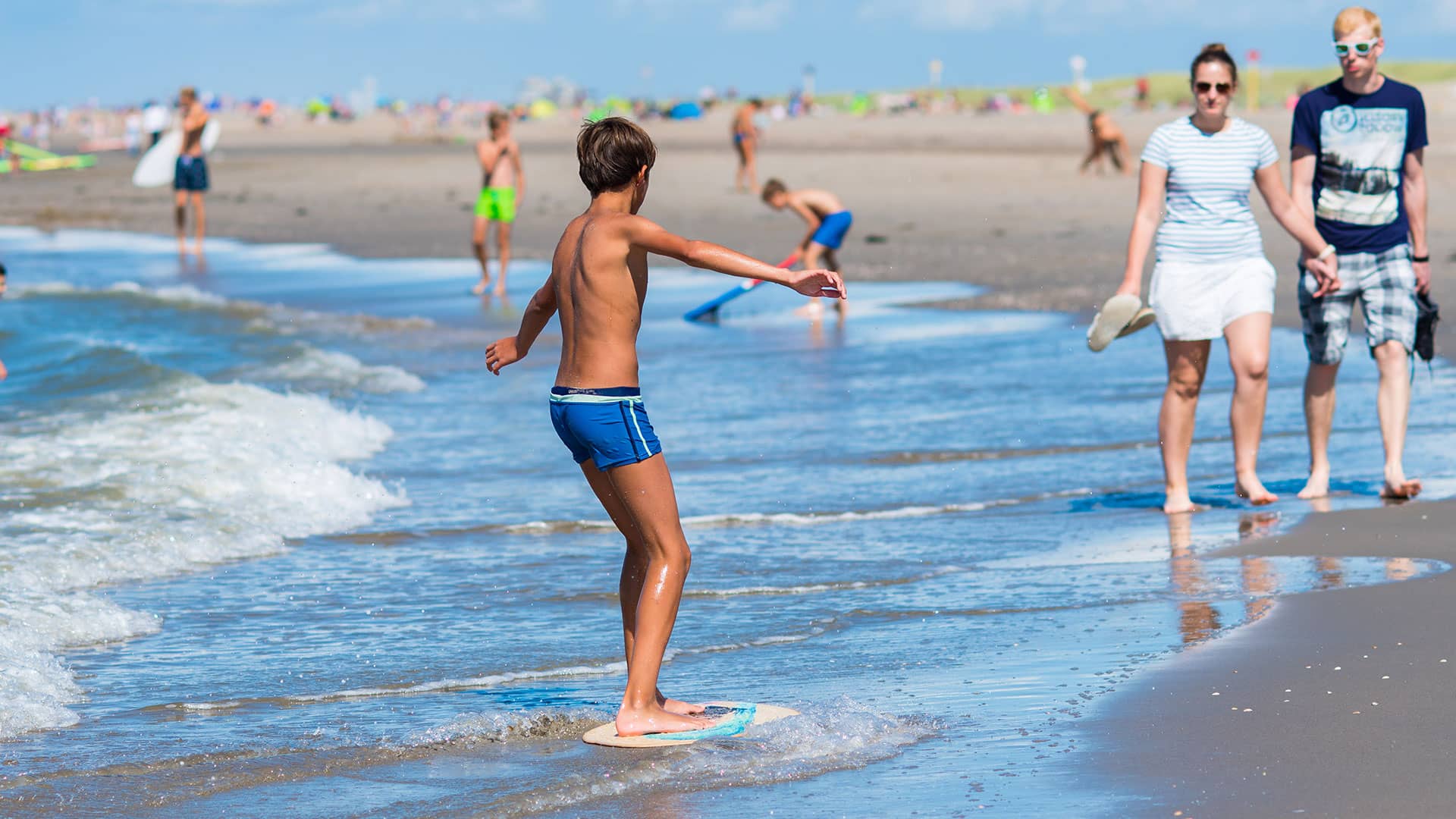 jongen met wakeboard in de vloedlijn op het strand in het westland