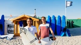 eigenaren Kaspar Hamminga & Erik Ringelberg op de foto met surfplanken in de hand voor hun surfschool Dutch Surf Academy op het strand in het Westland