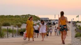 Strandopgang Beukel met strandbezoekers in zomerse kleding die van en naar het strand wandelen in warm avondlicht in het Westland