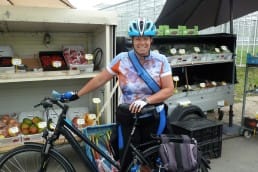 Marja van der Ende poseert met haar fiets voor een stalletje met streekproducten uit het Westland