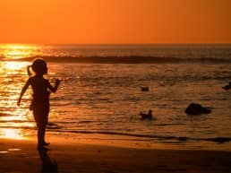 Strand-klein-meisje-bij-ondergaande-zon-