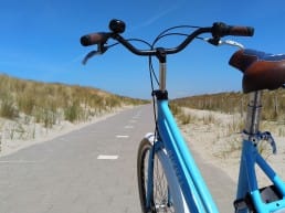 lichtblauwe fiets op het fietspad door de duinen bij Slag Arendsduin in het Westland