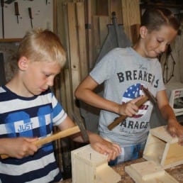 kinderen die met hout aan het timmeren zijn tijdens een workshop in Museum De Timmerwerf in het Westland