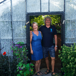 Hilde en Arnold Janssen poseren in de deuropening van een historische glazen kas van hun druivenkwekerij Nieuw Tuinzight in het Westland