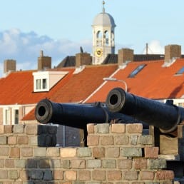 foto van twee antieke kanonnen bij het momument voor Admiraal Tromp in Ter Heijde in het Westland met op de achtergrond huisjes met rode daken aan de kust in het Westland