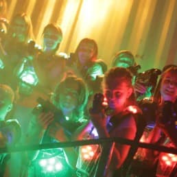 groepje kinderen staat tijdens een kinderfeestje in een donkere ruimte van van der ende racing inn met laserguns en laservesten klaar om te gaan lasergamen in het westland