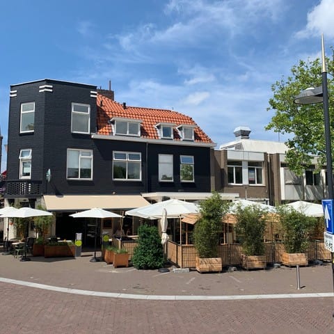 foto van het zonnige terras met witte parasols van Cafe de Slimmerick in Naaldwijk in het Westland