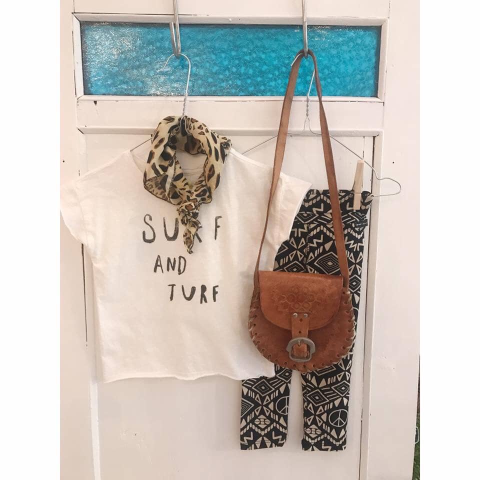 foto van een t-shirt, broek en handtas op een hangertje aan een deur tijdens een vintage markt bij Rumah conceptstore in het Westland